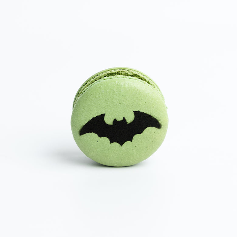 Green macaron with a black bat design on a white background for halloween